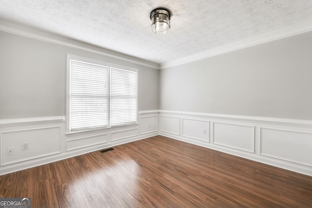 empty room with dark wood-type flooring, ornamental molding, and a textured ceiling