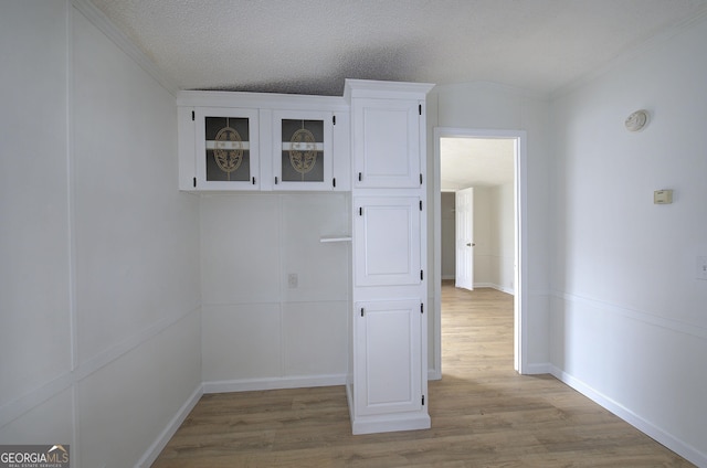 interior space featuring crown molding, light hardwood / wood-style floors, and a textured ceiling