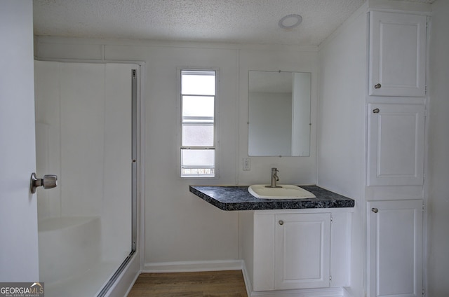 bathroom with vanity, hardwood / wood-style flooring, a textured ceiling, and walk in shower