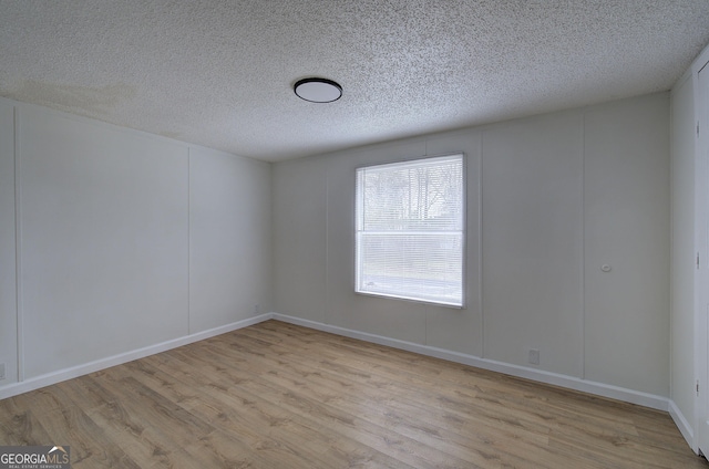 unfurnished room featuring light hardwood / wood-style floors and a textured ceiling