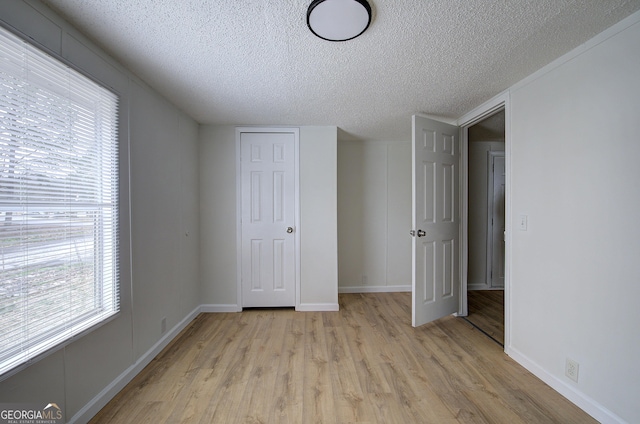 unfurnished bedroom with light hardwood / wood-style flooring, a closet, and a textured ceiling