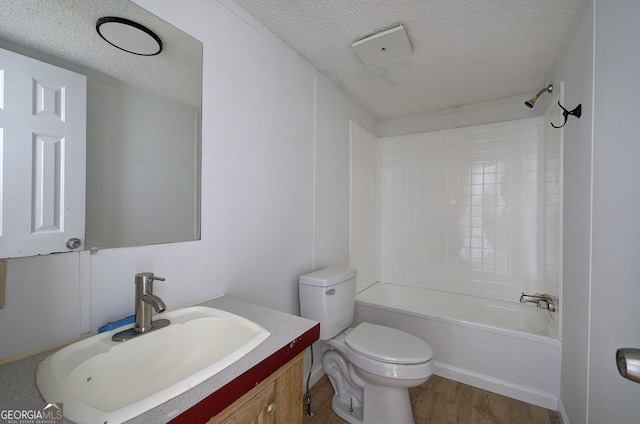 full bathroom with washtub / shower combination, toilet, a textured ceiling, vanity, and hardwood / wood-style flooring