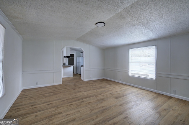 unfurnished room with wood-type flooring, a textured ceiling, and vaulted ceiling