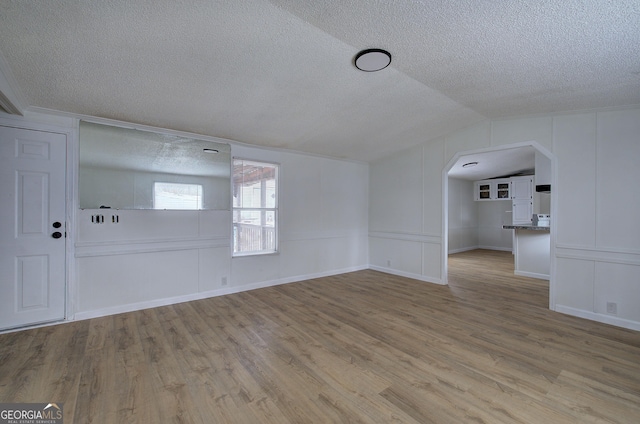 interior space featuring vaulted ceiling, light hardwood / wood-style floors, and a textured ceiling