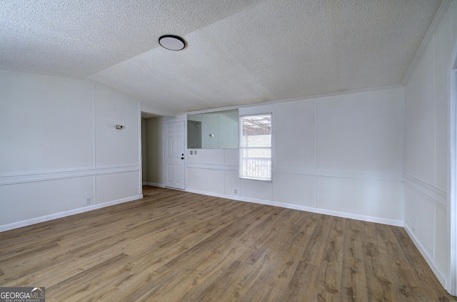 empty room featuring lofted ceiling, hardwood / wood-style flooring, electric panel, and a textured ceiling