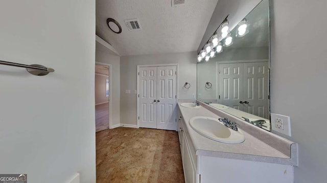 bathroom with lofted ceiling, a textured ceiling, and vanity