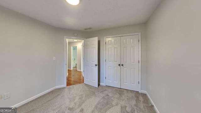 unfurnished bedroom featuring a closet and light carpet