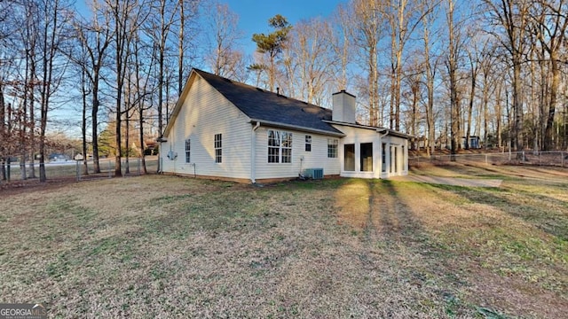 rear view of property featuring central AC and a lawn