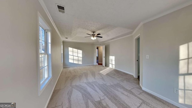 unfurnished room with ceiling fan, ornamental molding, a textured ceiling, light colored carpet, and a raised ceiling