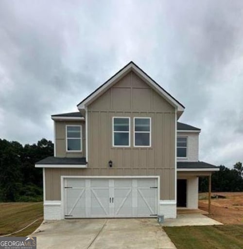 view of front of property with board and batten siding, a front yard, concrete driveway, and an attached garage