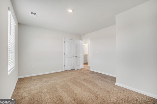 spare room featuring light carpet and baseboards