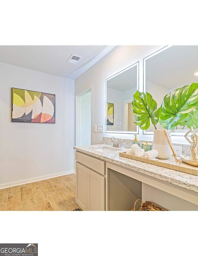 bathroom featuring visible vents, vanity, baseboards, and wood finished floors