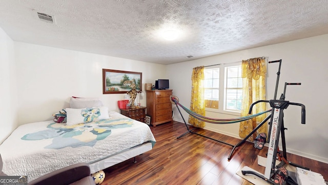 bedroom with dark hardwood / wood-style floors and a textured ceiling