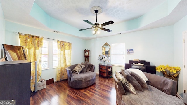 bedroom with dark hardwood / wood-style floors, ceiling fan, a tray ceiling, and a textured ceiling