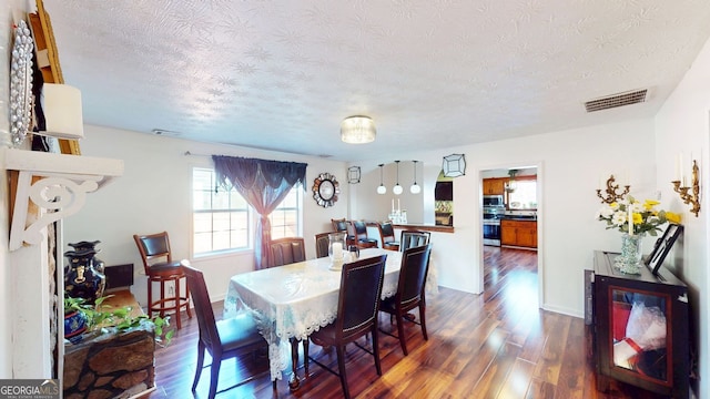 dining area with dark hardwood / wood-style flooring and a textured ceiling