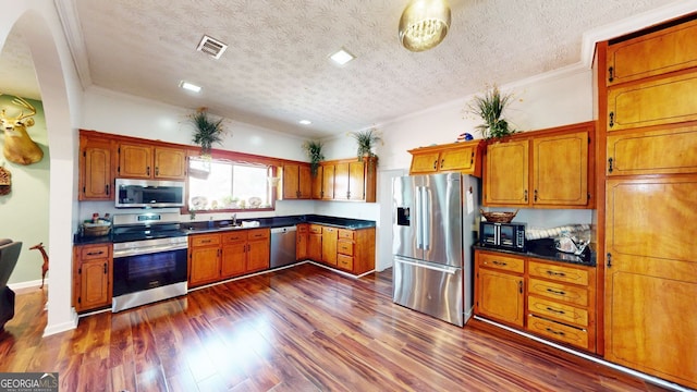 kitchen featuring sink, crown molding, appliances with stainless steel finishes, dark hardwood / wood-style floors, and a textured ceiling