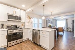 kitchen with appliances with stainless steel finishes, decorative light fixtures, and white cabinets