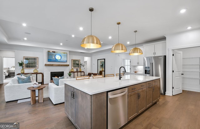 kitchen featuring a raised ceiling, appliances with stainless steel finishes, pendant lighting, and white cabinets