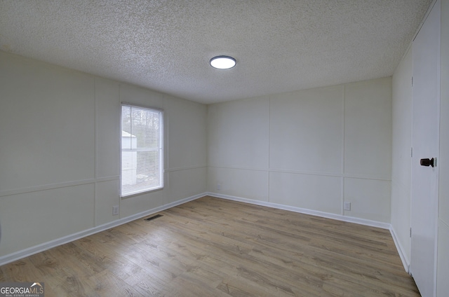 unfurnished room featuring a textured ceiling and light wood-type flooring