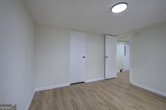 unfurnished room featuring a textured ceiling and light hardwood / wood-style floors