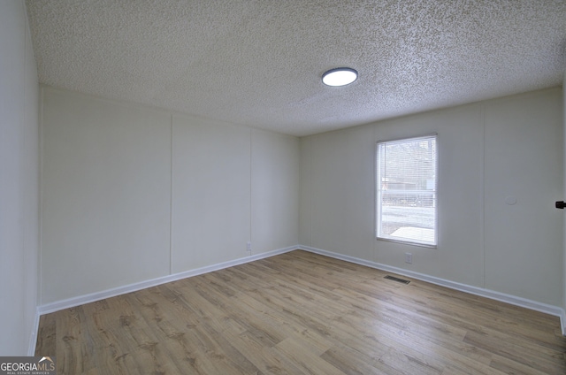 empty room featuring a textured ceiling and light wood-type flooring