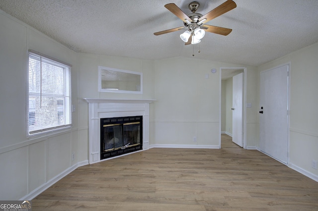 unfurnished living room with ceiling fan, light hardwood / wood-style floors, and a textured ceiling