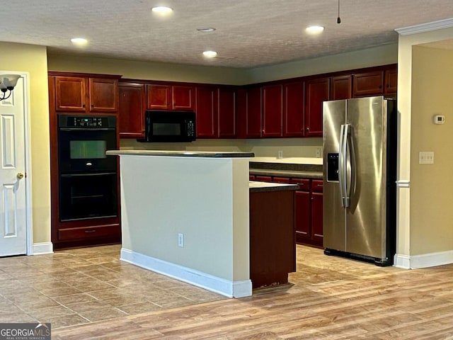 kitchen with light hardwood / wood-style flooring, black appliances, a center island, and a textured ceiling