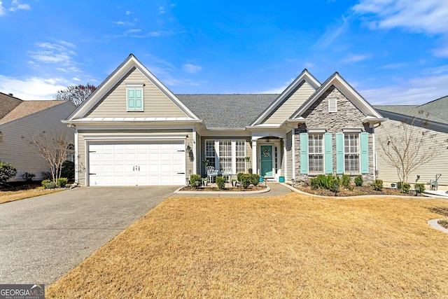 view of front of house featuring driveway, roof with shingles, a front lawn, a garage, and stone siding