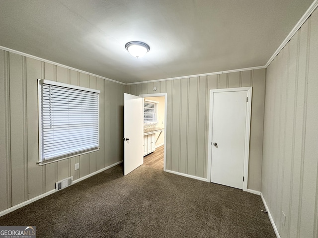 unfurnished bedroom with crown molding and dark carpet