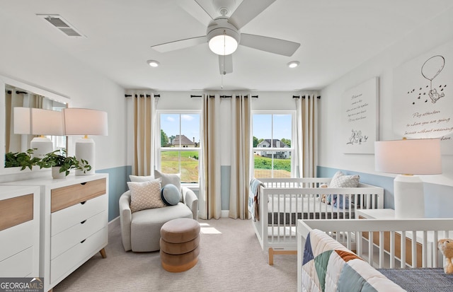 carpeted bedroom featuring a crib and ceiling fan