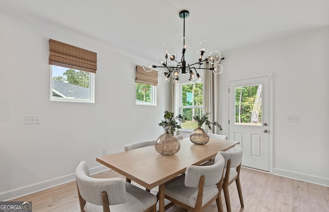 dining space with crown molding, light hardwood / wood-style floors, and a chandelier