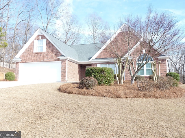 view of front of house with driveway, brick siding, and roof with shingles