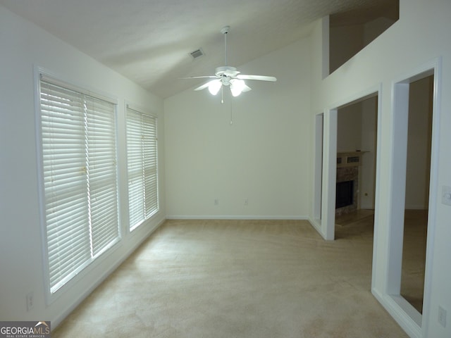 empty room with a fireplace, light colored carpet, visible vents, a ceiling fan, and baseboards