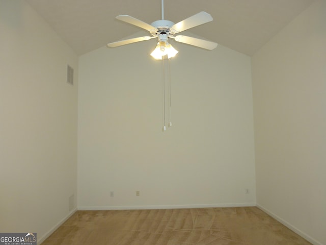 spare room featuring light carpet, baseboards, visible vents, and lofted ceiling