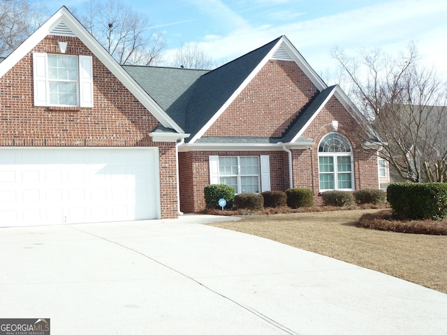 view of front of home with a shingled roof, concrete driveway, brick siding, and an attached garage