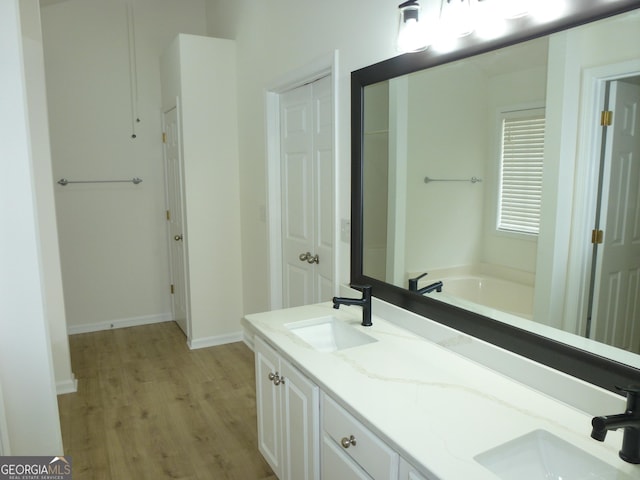 full bathroom with a sink, a bath, a closet, and wood finished floors