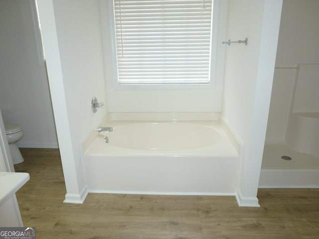 bathroom with a garden tub, vanity, wood finished floors, and toilet