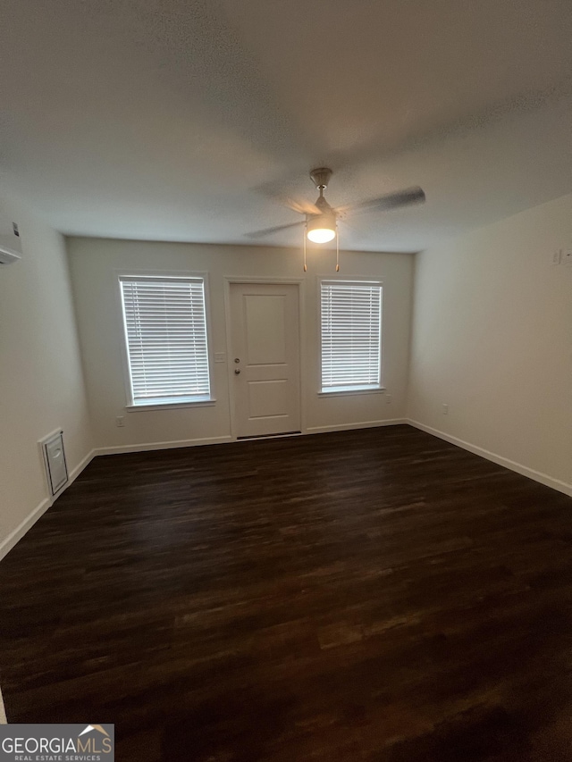 unfurnished room featuring plenty of natural light, dark wood-type flooring, and ceiling fan