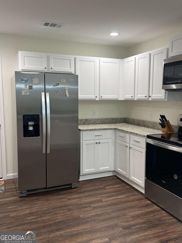 kitchen with stainless steel appliances, white cabinets, and dark hardwood / wood-style flooring