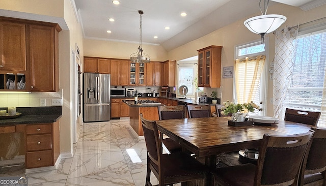 kitchen with crown molding, appliances with stainless steel finishes, backsplash, a center island, and decorative light fixtures