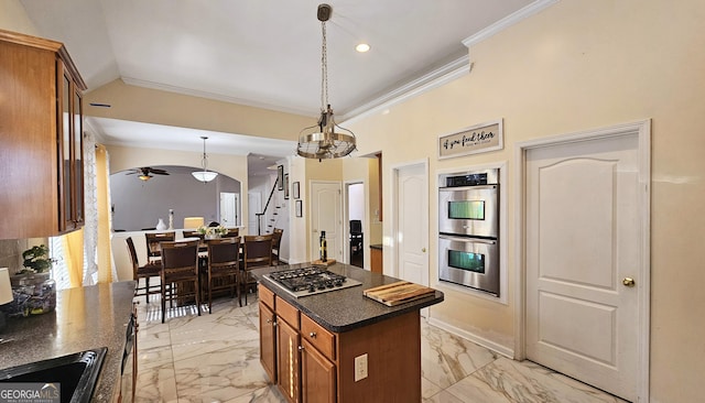 kitchen with pendant lighting, ornamental molding, a center island, ceiling fan, and stainless steel appliances