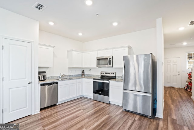 kitchen featuring sink, white cabinets, stainless steel appliances, light stone countertops, and light hardwood / wood-style flooring