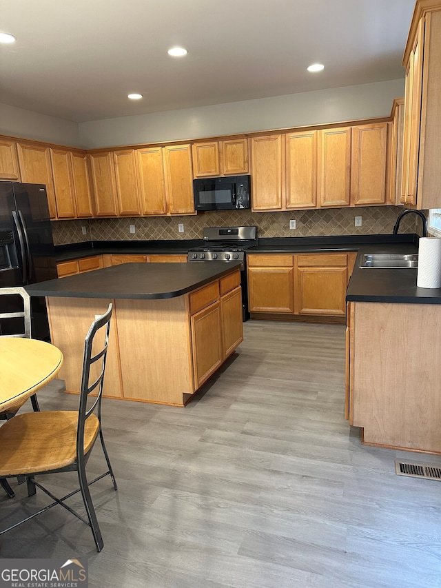 kitchen featuring a kitchen island, tasteful backsplash, sink, black appliances, and light hardwood / wood-style flooring