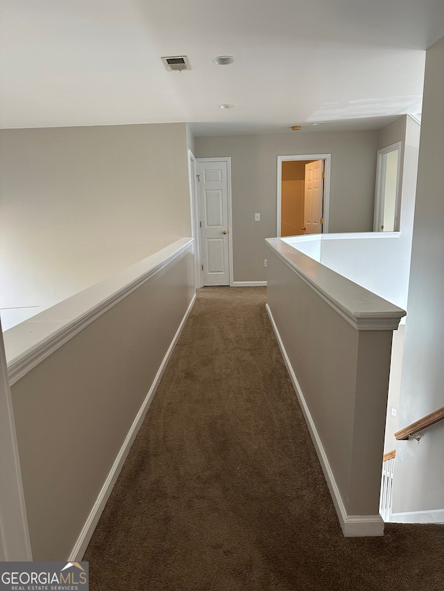 hallway with dark colored carpet