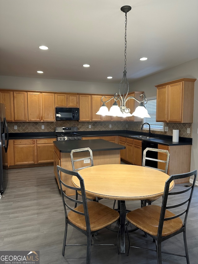 kitchen with a kitchen island, pendant lighting, sink, black appliances, and dark wood-type flooring