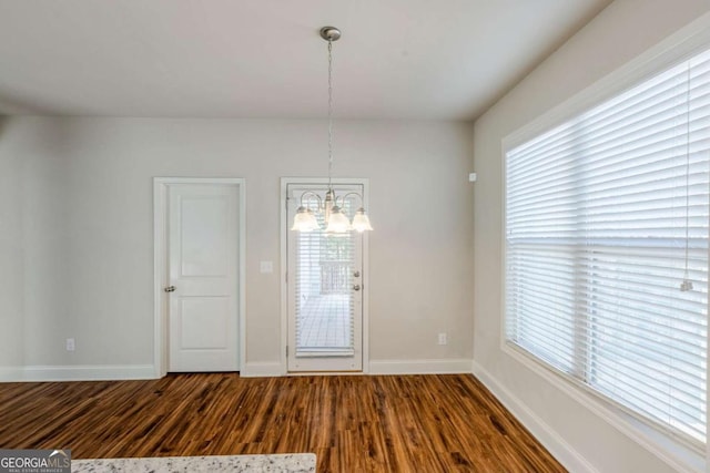 spare room with dark hardwood / wood-style flooring and a notable chandelier