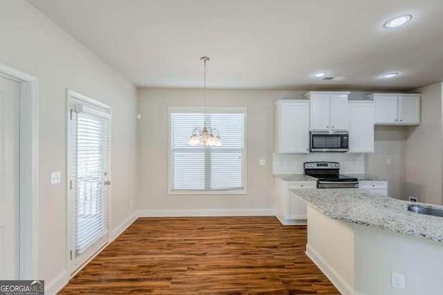 kitchen with dark wood-type flooring, white cabinetry, light stone counters, appliances with stainless steel finishes, and pendant lighting