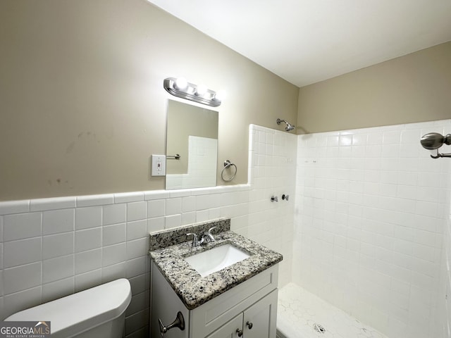 bathroom featuring vanity, tiled shower, tile walls, and toilet