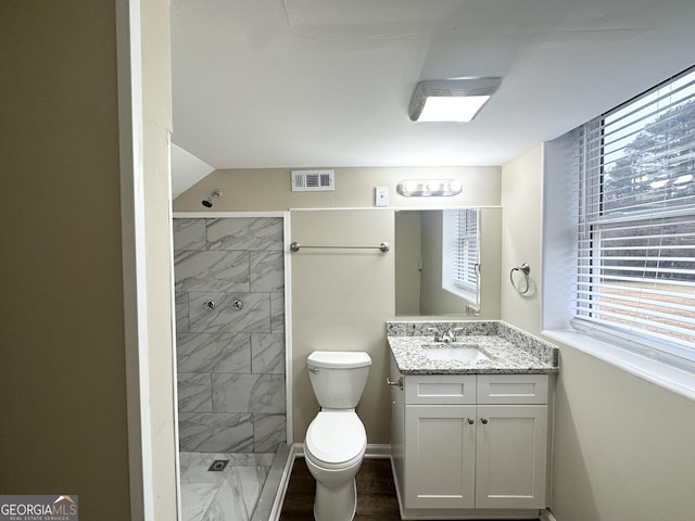 bathroom with vanity, toilet, and a tile shower