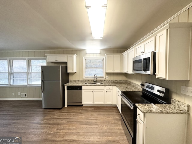 kitchen with sink, stainless steel appliances, a wealth of natural light, light stone countertops, and white cabinets